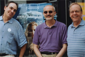 Paul, Dave, and Doug stand in front of an "Another Earth" movie poster at the Downer Theater.
